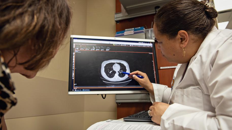 A doctor using computer to explain a condition to patient.