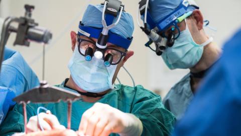 Two gowned and masked surgeons operating